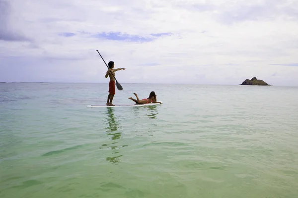 Beachboy med tjej i bikini paddla ombord — Stockfoto