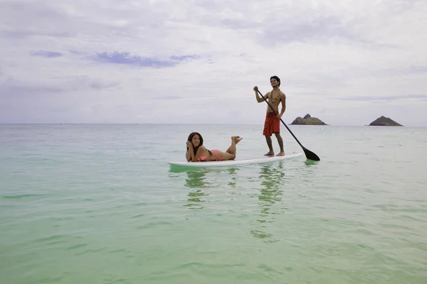 Garçon de plage avec fille en bikini sur planche à pagaie — Photo