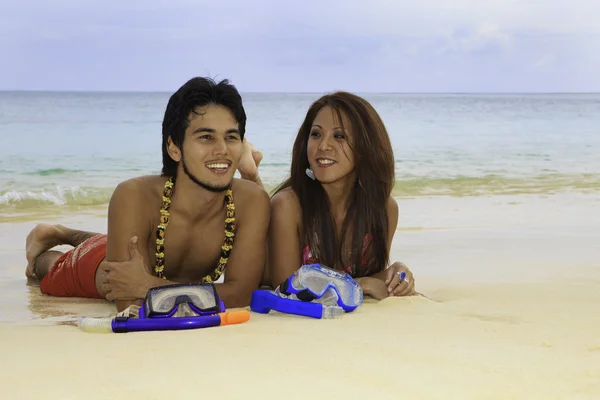 Asian couple lounging on the sand of a hawaii beach — Stock Photo, Image