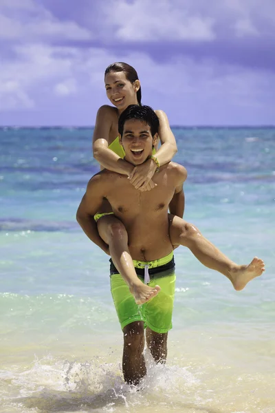 Casal no oceano cavalgando piggyback — Fotografia de Stock