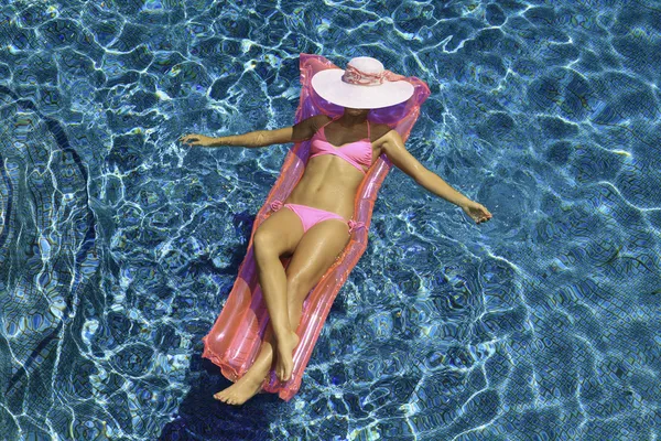 Chica en bikini rosa flotando en una piscina — Foto de Stock