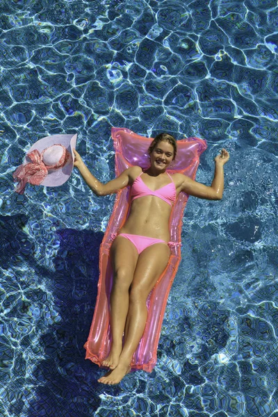 女孩的粉色比基尼泳装在游泳池中漂浮 — 图库照片