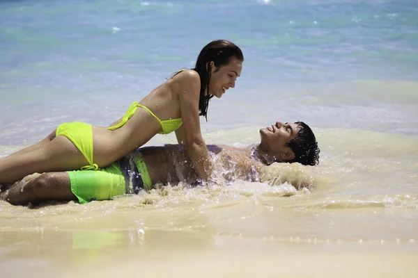 Пара, играющая на краю воды на гавайском пляже — стоковое фото