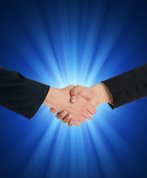 Handshaking in front of blue light — Stock Photo, Image