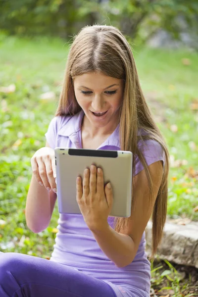 Piękna kobieta z komputera typu tablet w parku — Zdjęcie stockowe