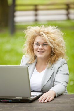 Woman using laptop in open office clipart