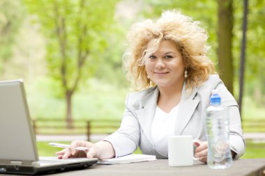 Woman using laptop in park clipart