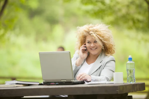 Γυναίκα χρησιμοποιώντας το κινητό και το laptop το ανοιχτό γραφείο — Φωτογραφία Αρχείου