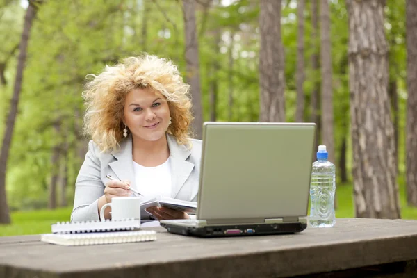女子在公园木制桌上使用便携式计算机 — 图库照片