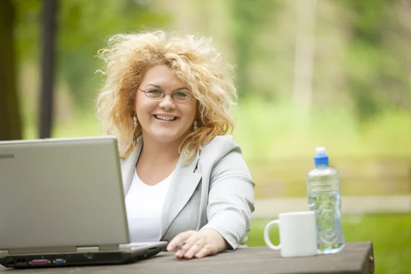 Mujer de negocios feliz usando el portátil en el parque —  Fotos de Stock