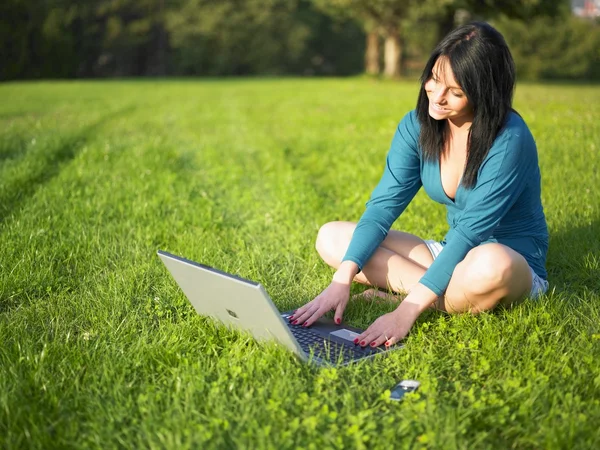 Mujer joven usando el ordenador portátil en el parque — Foto de Stock