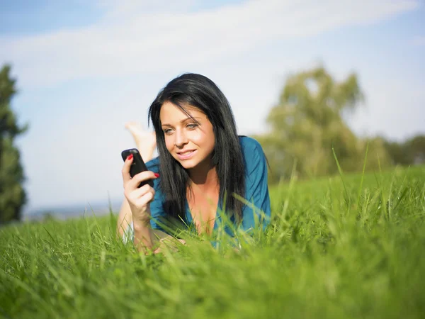 Jovem mulher usando telefone celular no parque — Fotografia de Stock