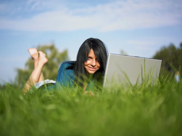 Park yerinde dizüstü bilgisayar kullanan genç bir kadın — Stok fotoğraf