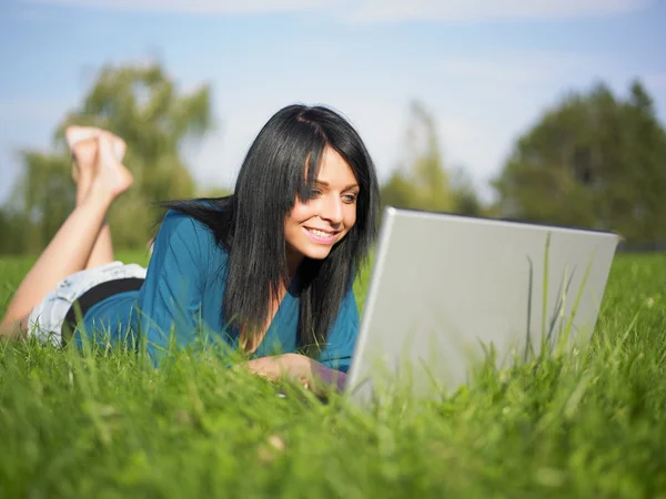 Giovane donna che utilizza il computer portatile nel parco — Foto Stock