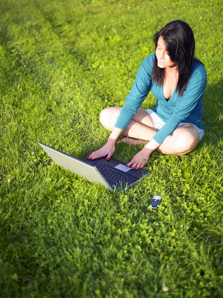 Νεαρή γυναίκα που χρησιμοποιεί φορητό υπολογιστή στο πάρκο — Φωτογραφία Αρχείου
