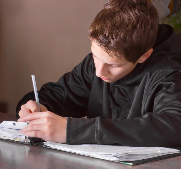 Мальчик-подросток, выполняющий домашнюю работу — стоковое фото