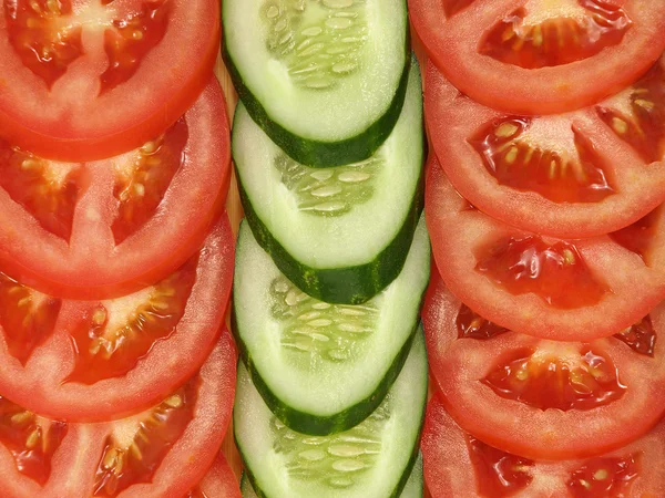 Segmenten van tomaat en komkommer als achtergrond. — Stockfoto
