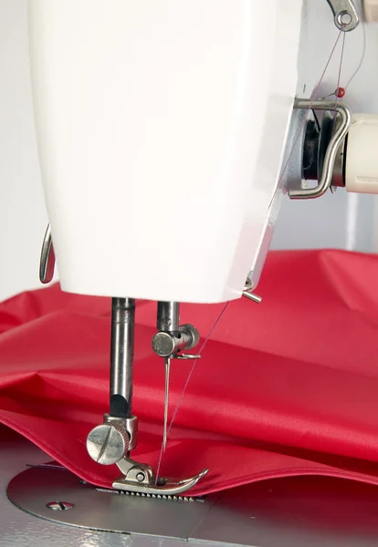 La máquina de coser está cosiendo tela roja — Foto de Stock
