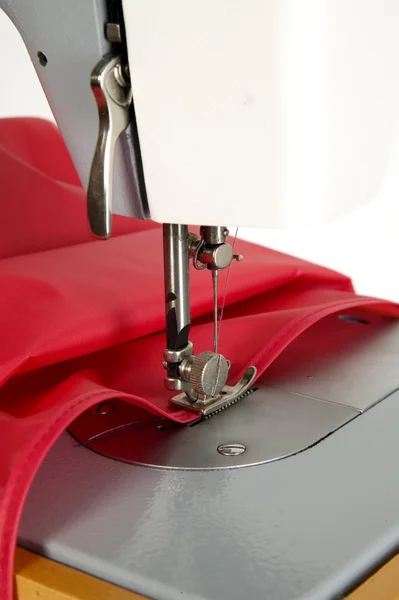 La máquina de coser está cosiendo tela roja —  Fotos de Stock