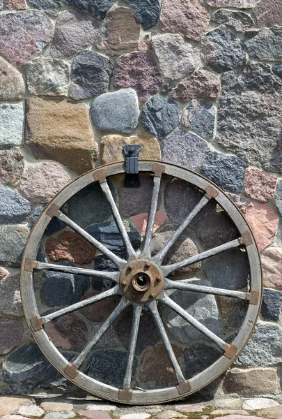 Old wooden wheel is placed near wall — Stock Photo, Image