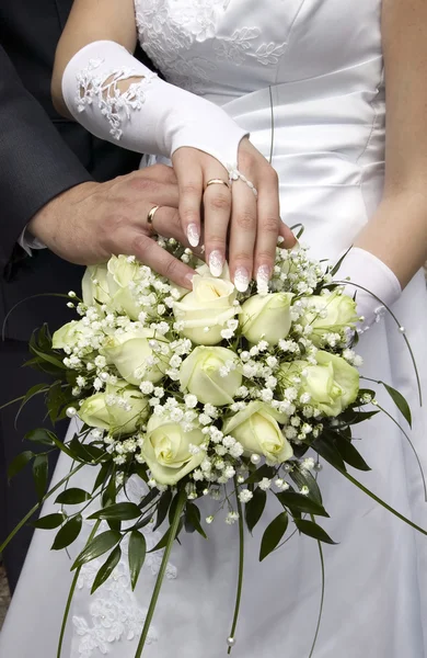 Groom and bride showing gold rings and flowers — Stock Photo, Image