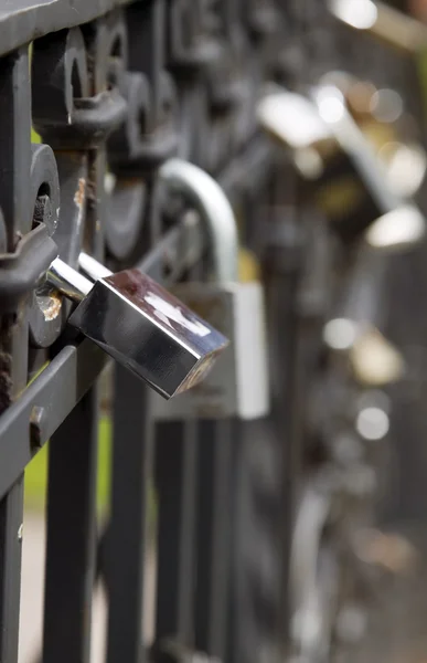 Många metall lås hänger på svart staket — Stockfoto