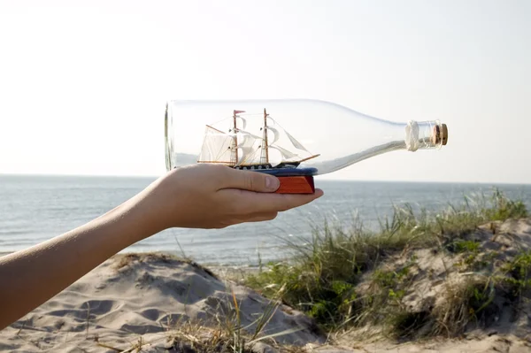 Homem está segurando navio em miniatura em garrafa — Fotografia de Stock