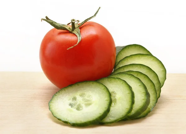 Cucumber and tomato on a wooden board — Stock Photo, Image
