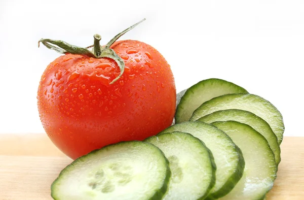 Cucumber and tomato on a wooden board — Stock Photo, Image