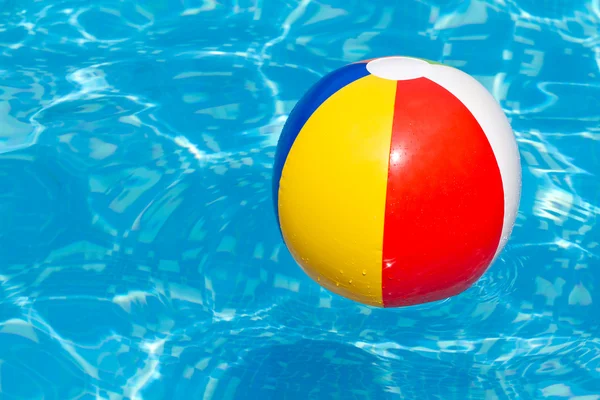 Una colorida pelota de playa flotando en una piscina Imagen de stock
