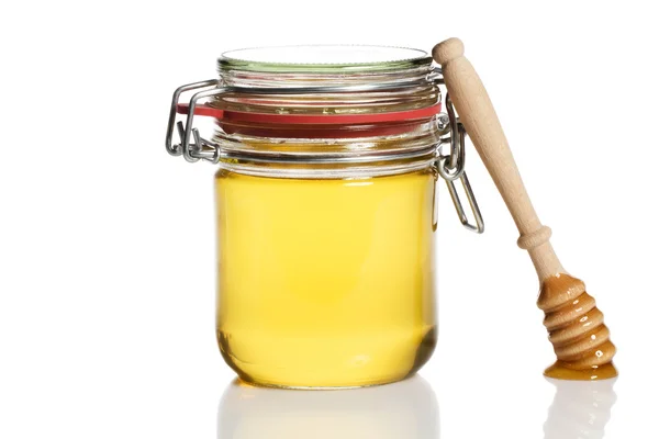 Mel coberto mel dipper inclinando-se em um frasco de mel — Fotografia de Stock