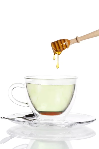 Gotas de miel de un cazo de miel en una taza de vidrio con té verde —  Fotos de Stock