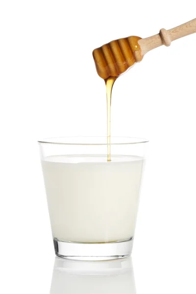 Mel caindo de um mergulhador de mel em um jarro com leite — Fotografia de Stock