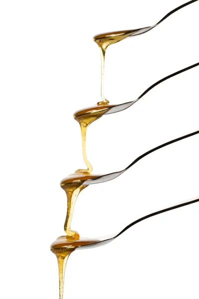 Honey falling over four spoons — Stock Photo, Image