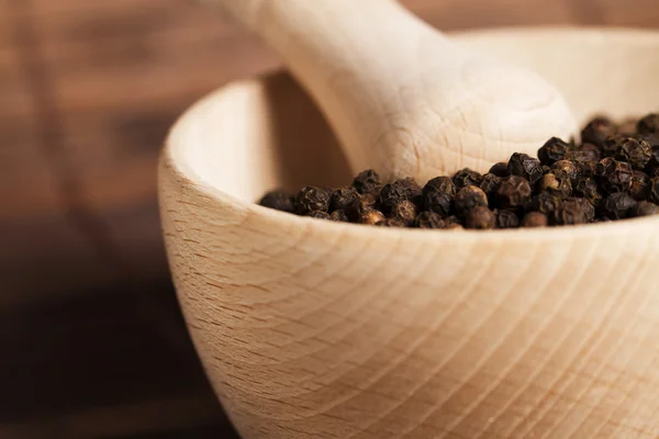 Closeup of peppercorns in a wooden mortar — Stock Photo, Image