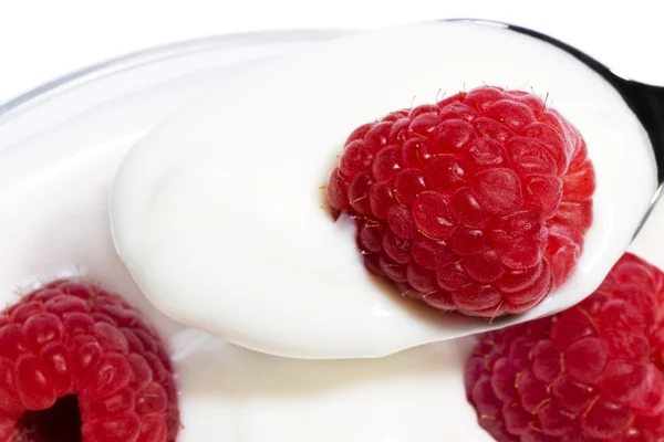 Närbild av en hallon på en sked med yoghurt — Stockfoto