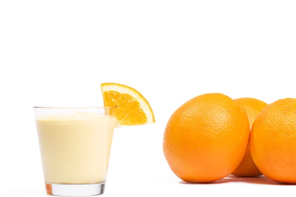 Stück einer Orange auf einem Milchshake vor Orangen — Stockfoto