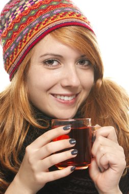 Young smiling woman with winter cap warming-up with tea clipart