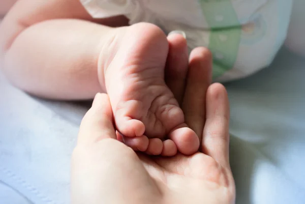 Рука мами тримає ногу дитини в долоні — стокове фото
