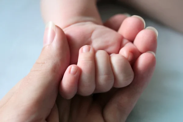 Die Hand der Mutter hält eine Hand des Babys in einer Handfläche — Stockfoto