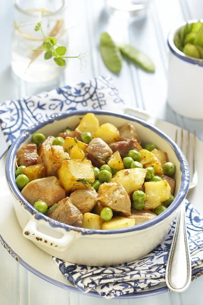 Ragoût de pommes de terre, porc et pois verts sur table bleue — Photo