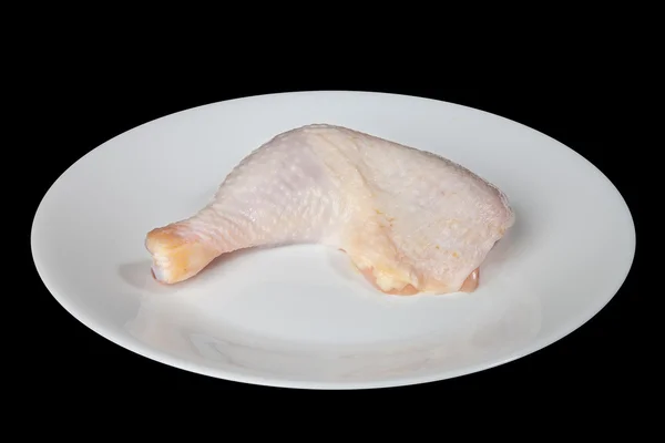 Chicken leg on a white plate is isolated on a black background — Stock Photo, Image