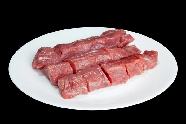 Stykker af råt kød på en hvid plade - Stock-foto