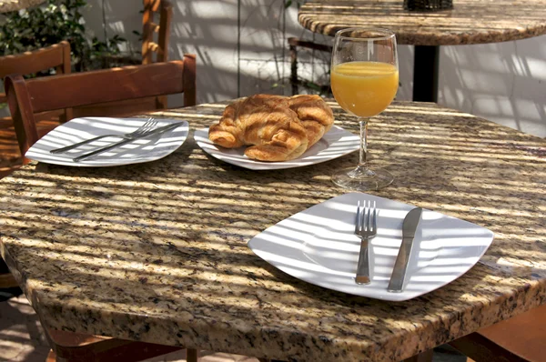 Semi outdoor tropical cafe table with juice and croissants — Stock Photo, Image