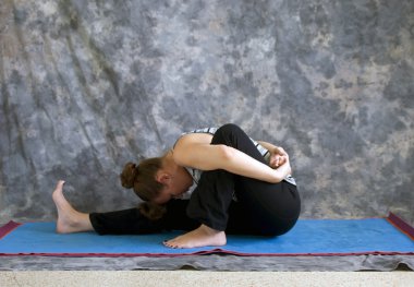 Woman doing Yoga posture Marichyasana I or bound forward fold po clipart
