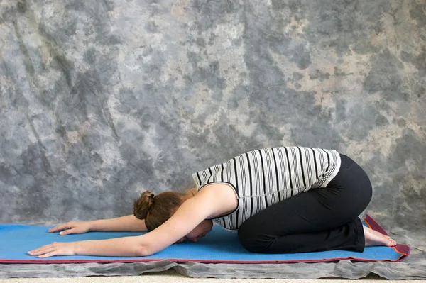 Kvinnan gör yoga posture balasana eller childs pose — Stockfoto