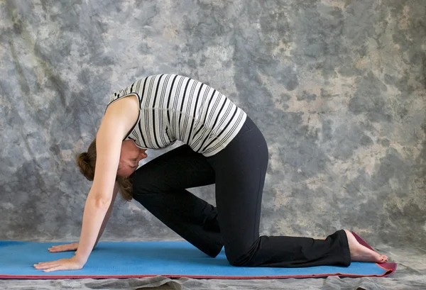 Kvinnan gör yoga posture marjaryasana variation eller stark katt po — Stockfoto