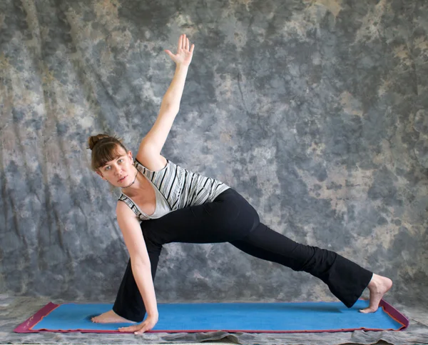Mulher fazendo postura Yoga Parivrtta Parsvakonasana ou Revolved Ex — Fotografia de Stock
