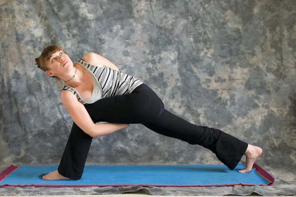 Mulher fazendo postura de Yoga Parsvakonasana ou limitado lado estendido A — Fotografia de Stock