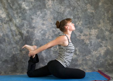 genç kadın Yoga duruş kapotasana veya güvercin poz variati yapıyor